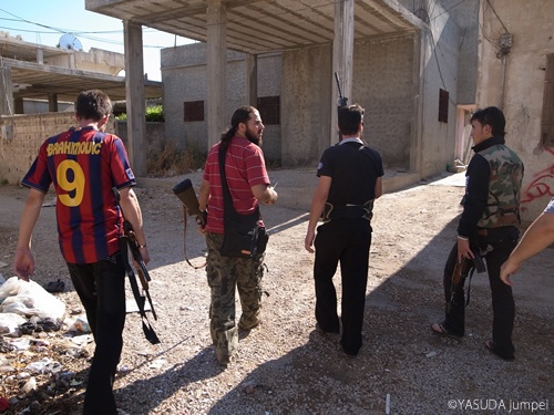 政府軍への狙撃に向かう反政府軍。レアル応援部隊のはずなのにバルセロナのユニフォームを着ている男が＝2012年7月17日