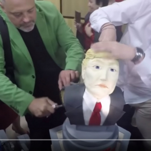 クリミアのテレビ局のジャーナリストが開局60周年記念でトランプ大統領型ケーキを切り刻む